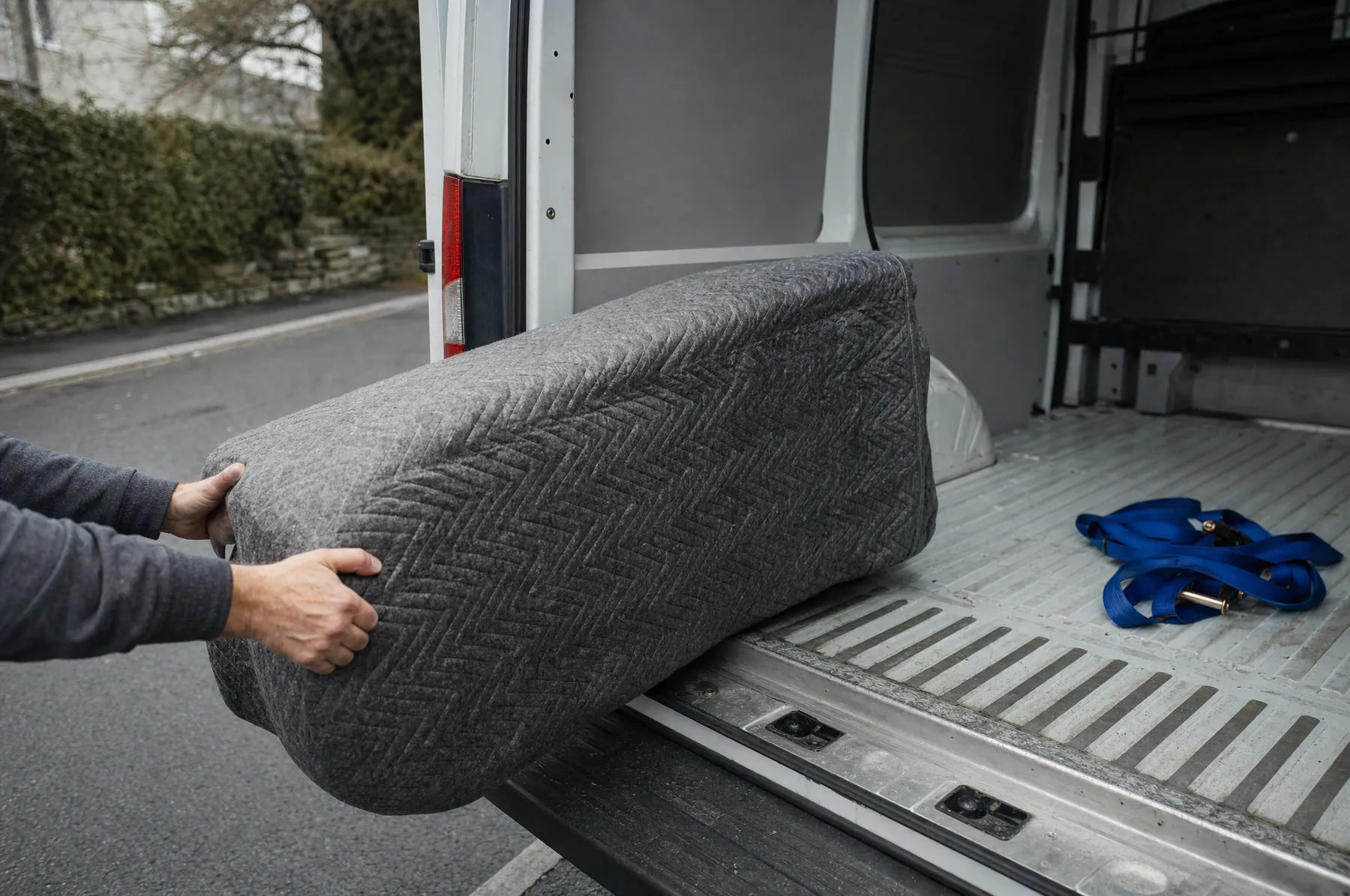 Ein einzelnes, mit einer Decke geschütztes Möbelstück an der Ladekante eines Transporters.